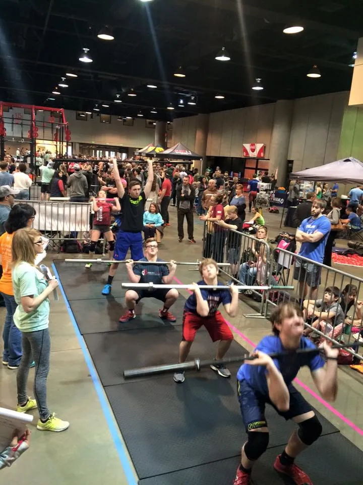 Five junior boys mid front-squat with judge scoring