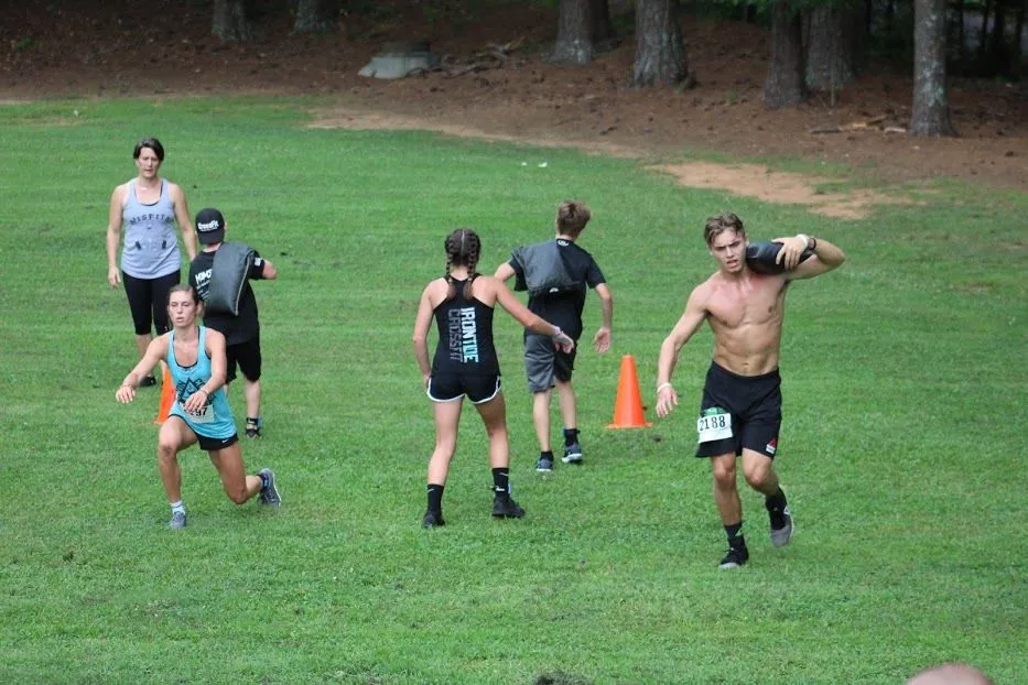 Athletes carrying sandbags through an outdoor run
