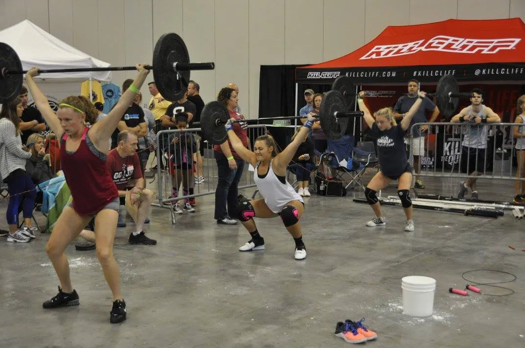 Three junior athletes mid overhead squat on the competition floor