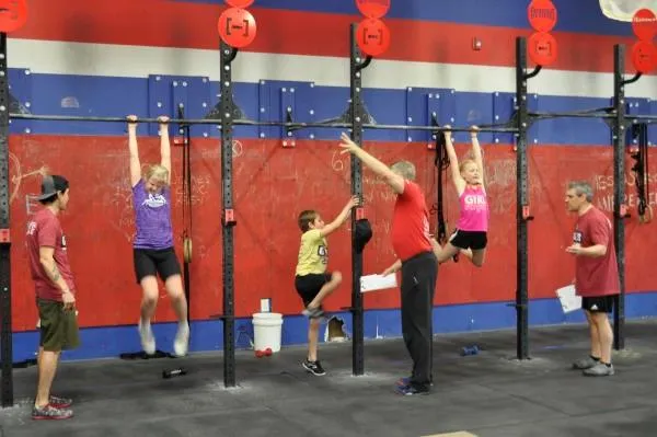 Youngest athletes hanging from the rig with judges scoring