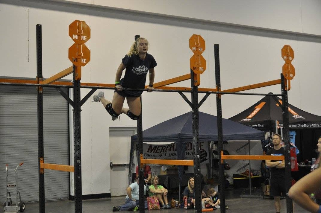 Junior athlete locked out at the top of a bar muscle-up