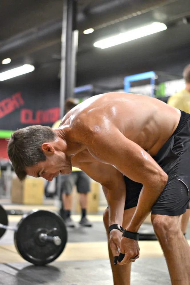 A masters athlete bent over the bar mid-workout