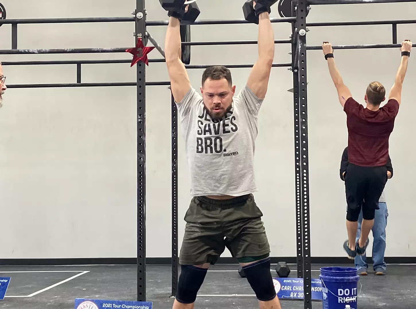 A masters athlete pressing dumbbells overhead at a tour championship