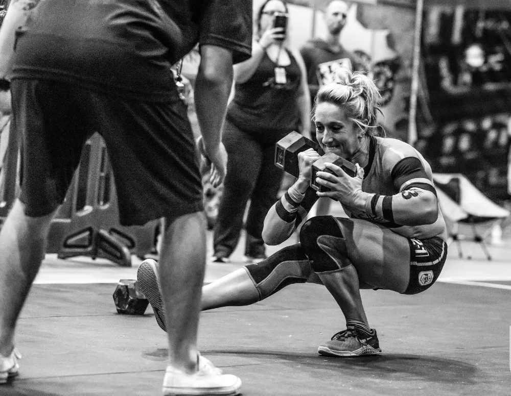 A masters athlete in a deep squat holding a dumbbell at the chest